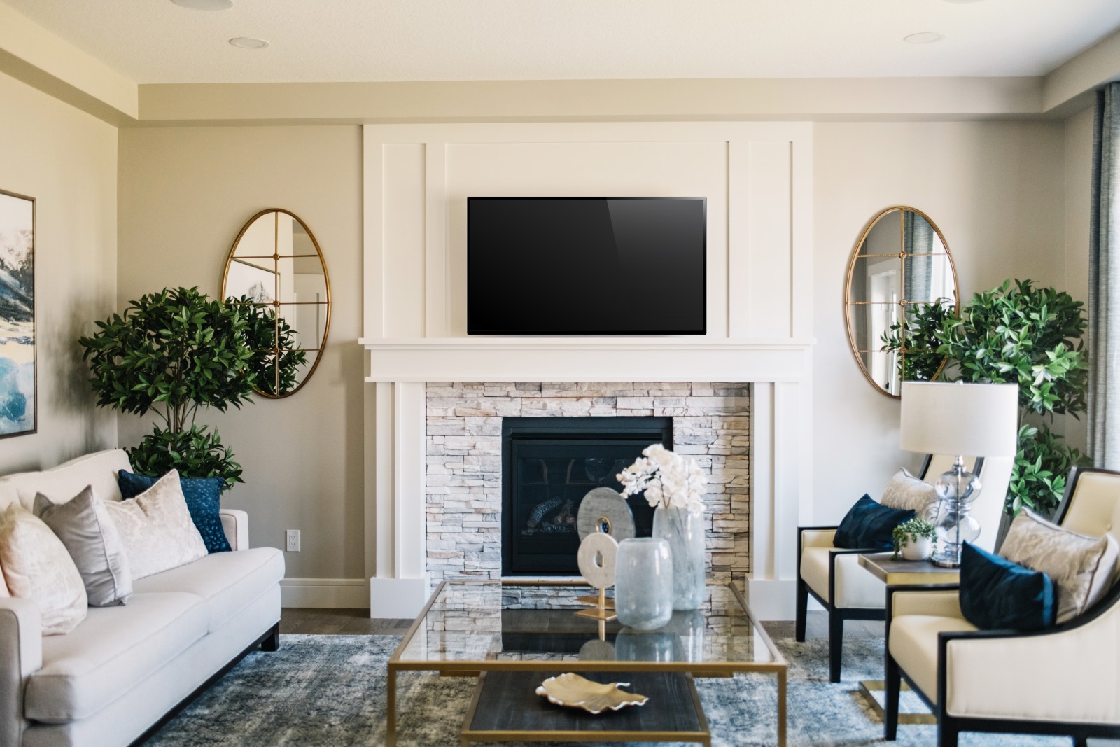 Traditional great room in the Julian showhome with stone surround on fireplace and traditional surround with complementing wall panel above mantel