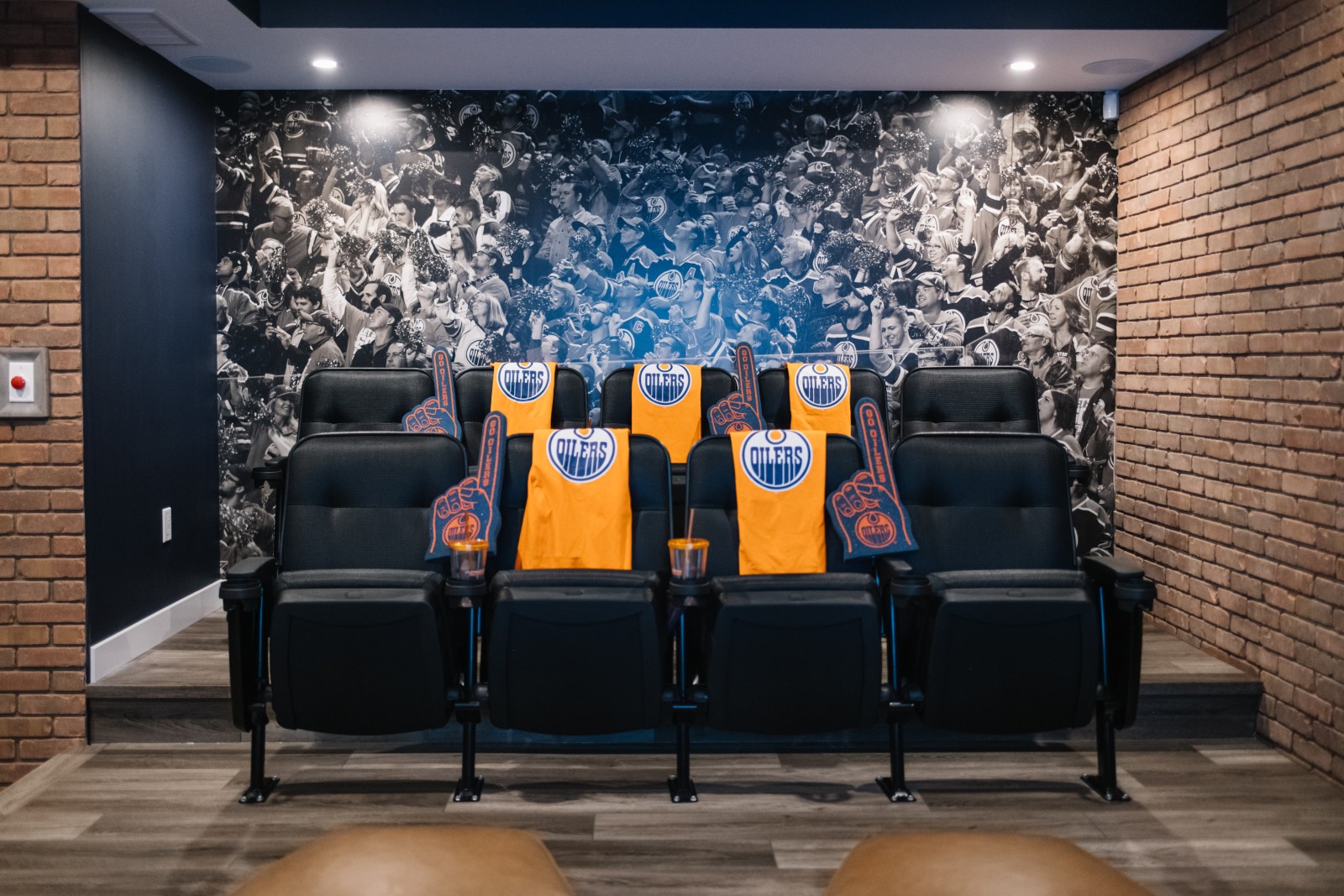 Oilers Fan Cave in the Nysa showhome with stadium seats in front of floor to ceiling, black and white mural of a crowd in an arena