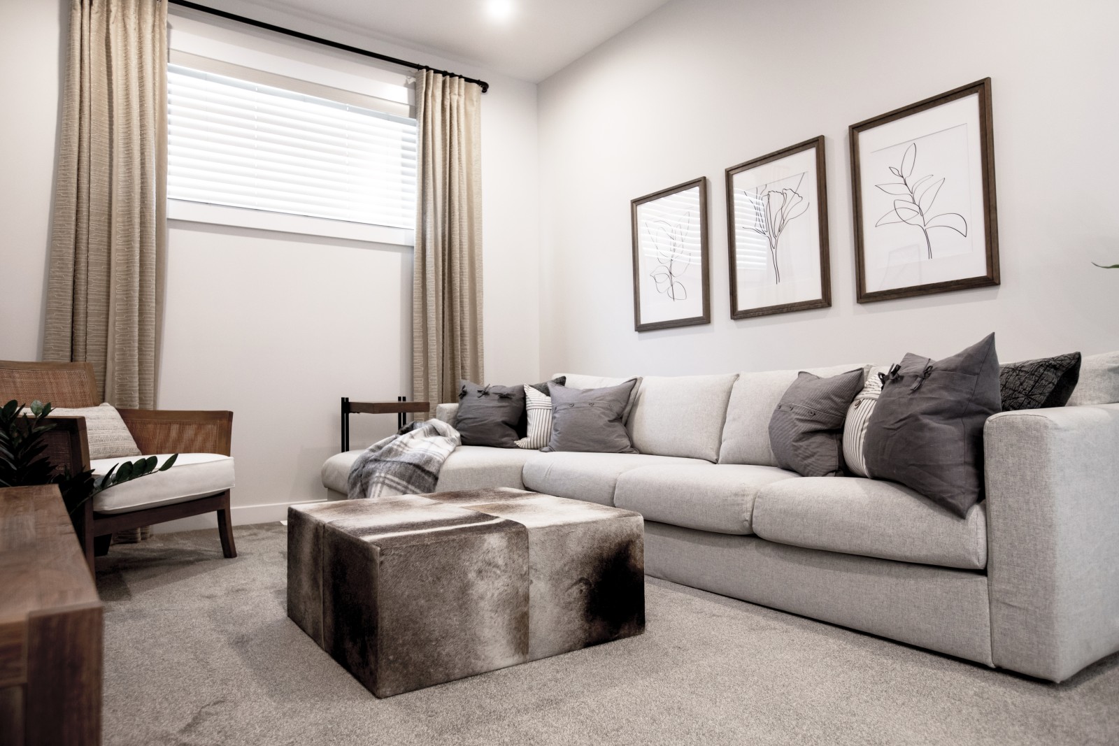 Bonus room in the Odessa showhome with comfy couch, neutral accents and warm tones