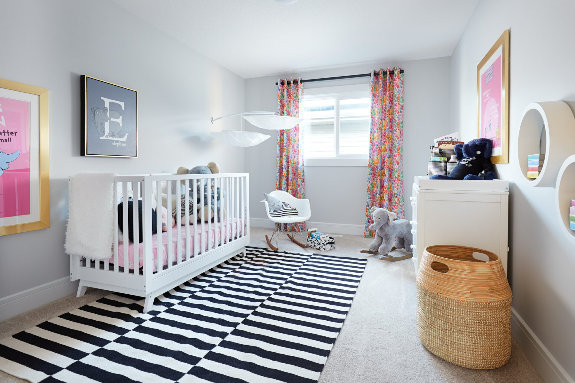 A minimalistic nursery with black and white checkered area rug, white crib and dresser with pink accents in bedding and curtains