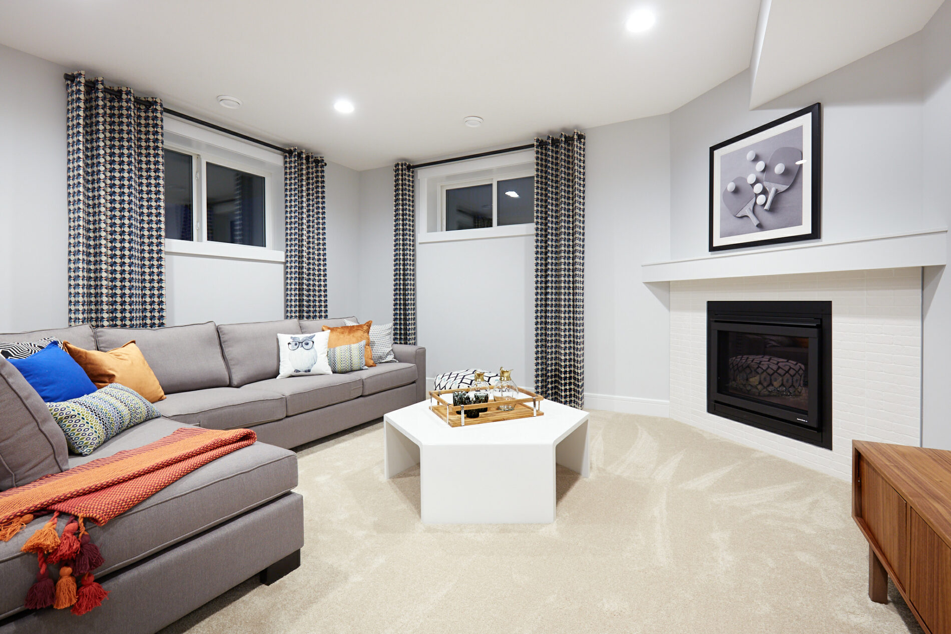 Basement in the Kalliope showhome with corner fireplace and inviting grey sectional couch
