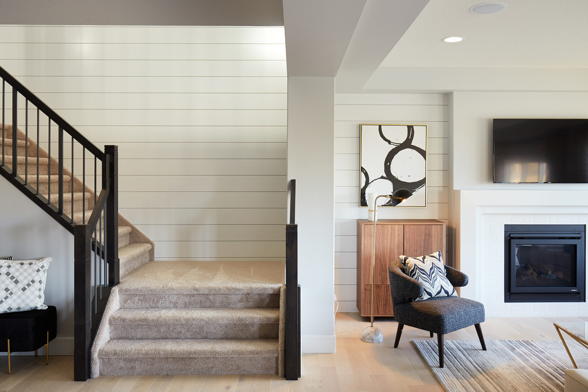 Stairwell wall and wall flanking the fireplace in the great room featuring sleek, white shiplap detail