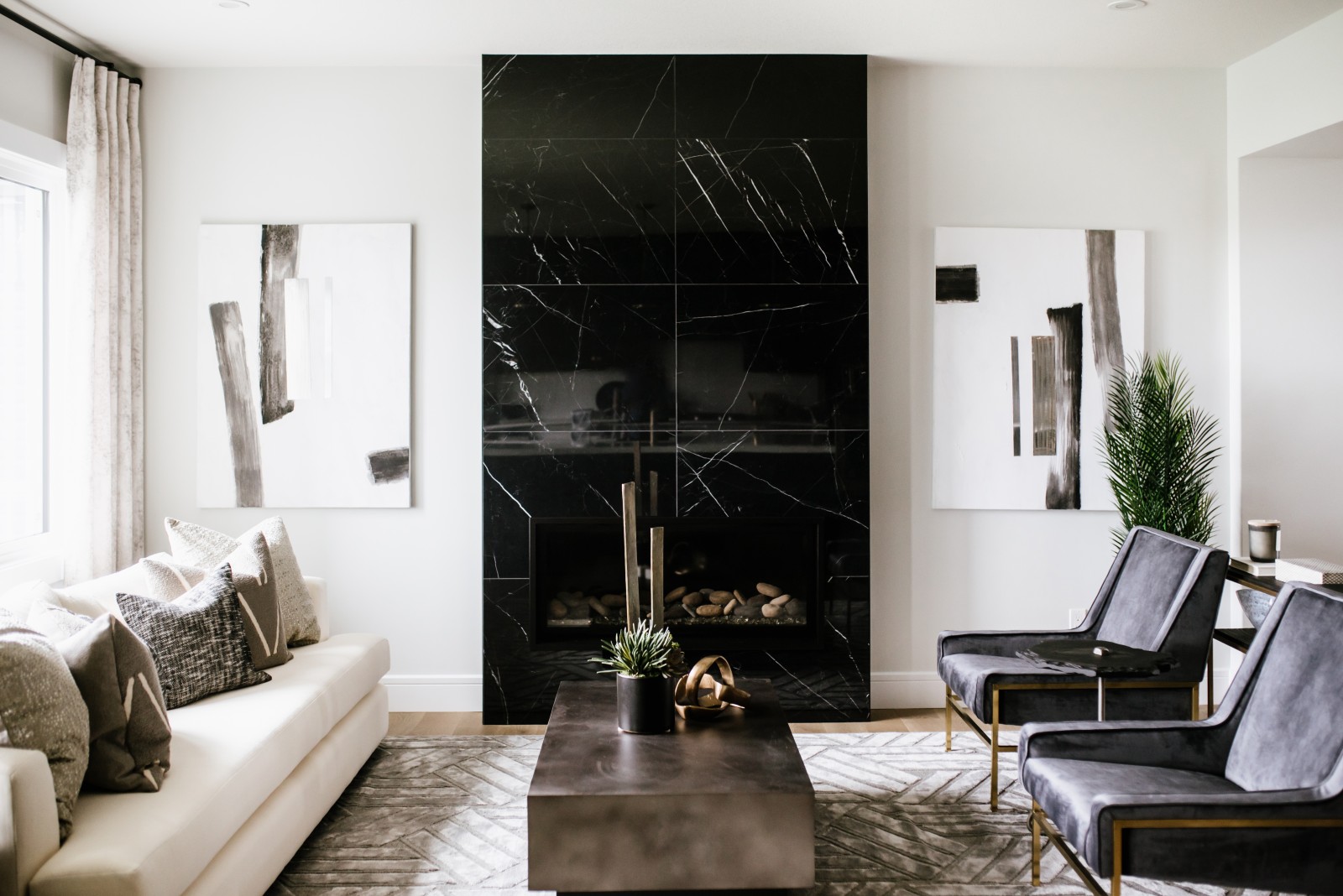 Statement great room fireplace clad in modern large format black tile flanked on either side with modern art