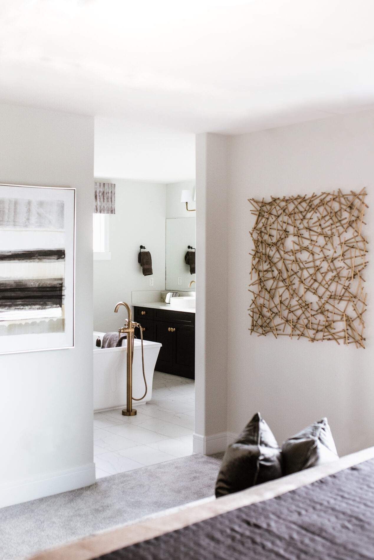 Peek of the master enuite from the bedroom with art flanking the entrance to the ensuite and the freestanding tub and vanity in view