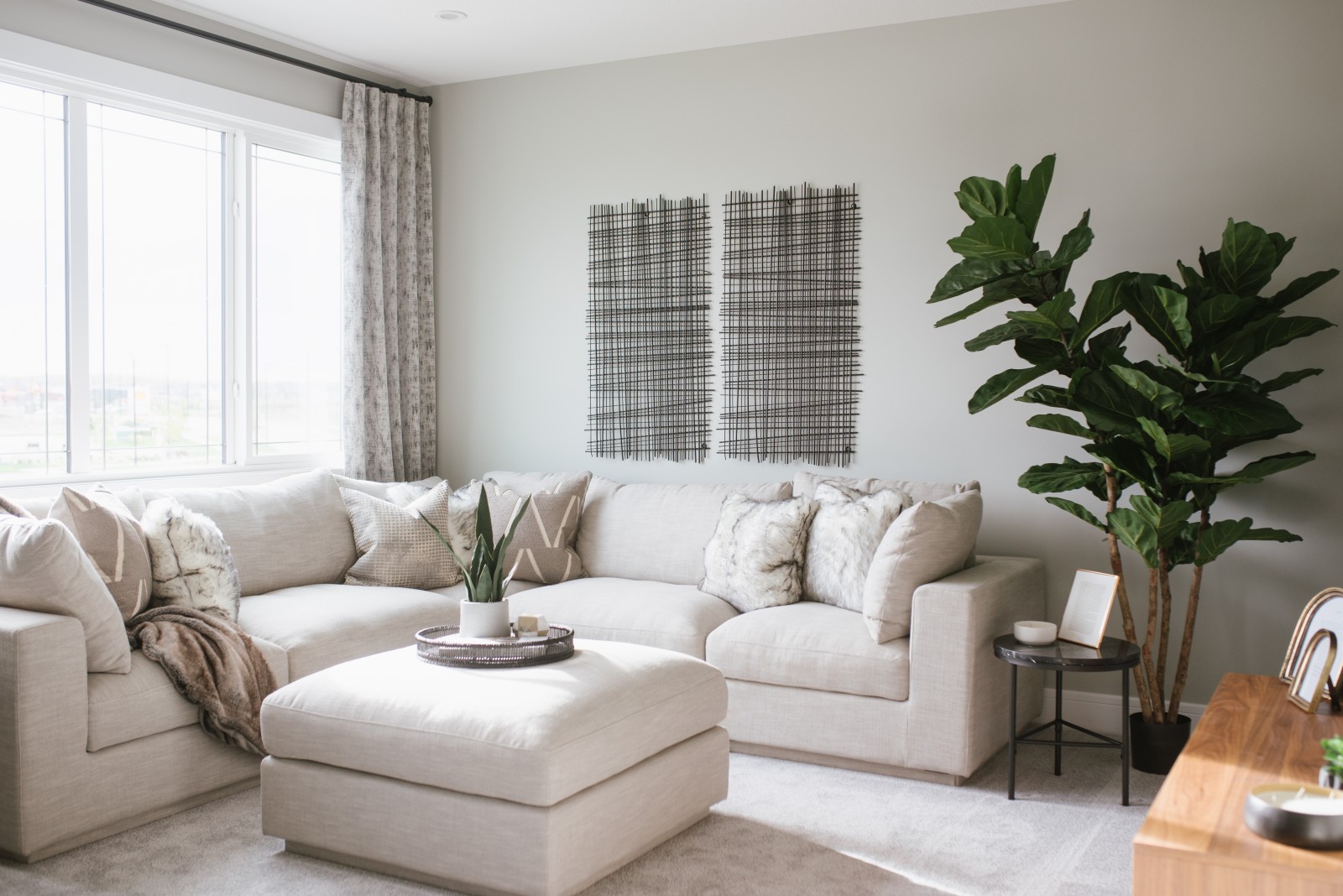 Inviting bonus room with high ceilings featuring big windows to the front of the house, a cozy white sectional couch and large textured art pieces on the wall