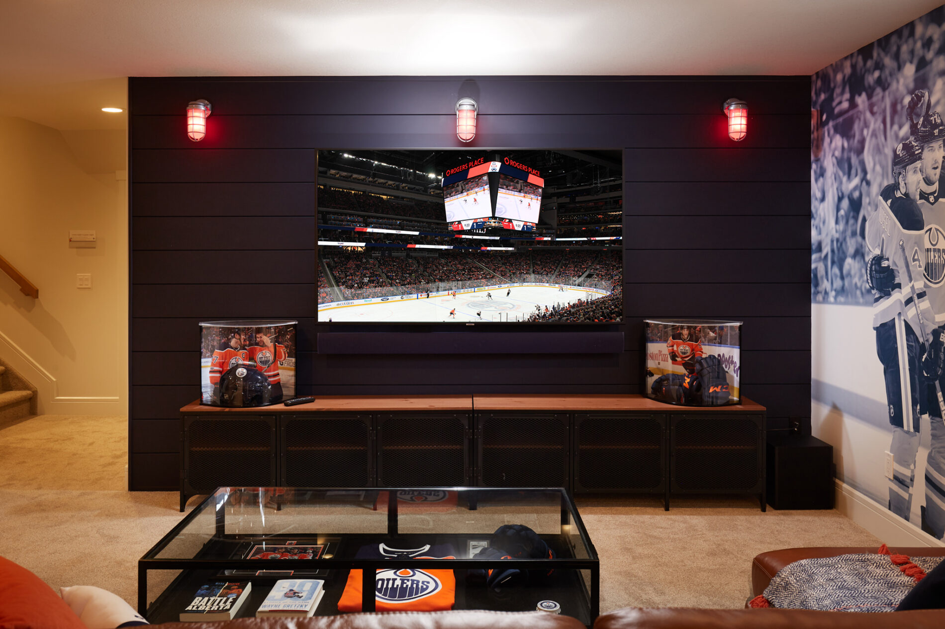 A tv mounted on a feature wall of dark blue shiplap with goal lights lit up