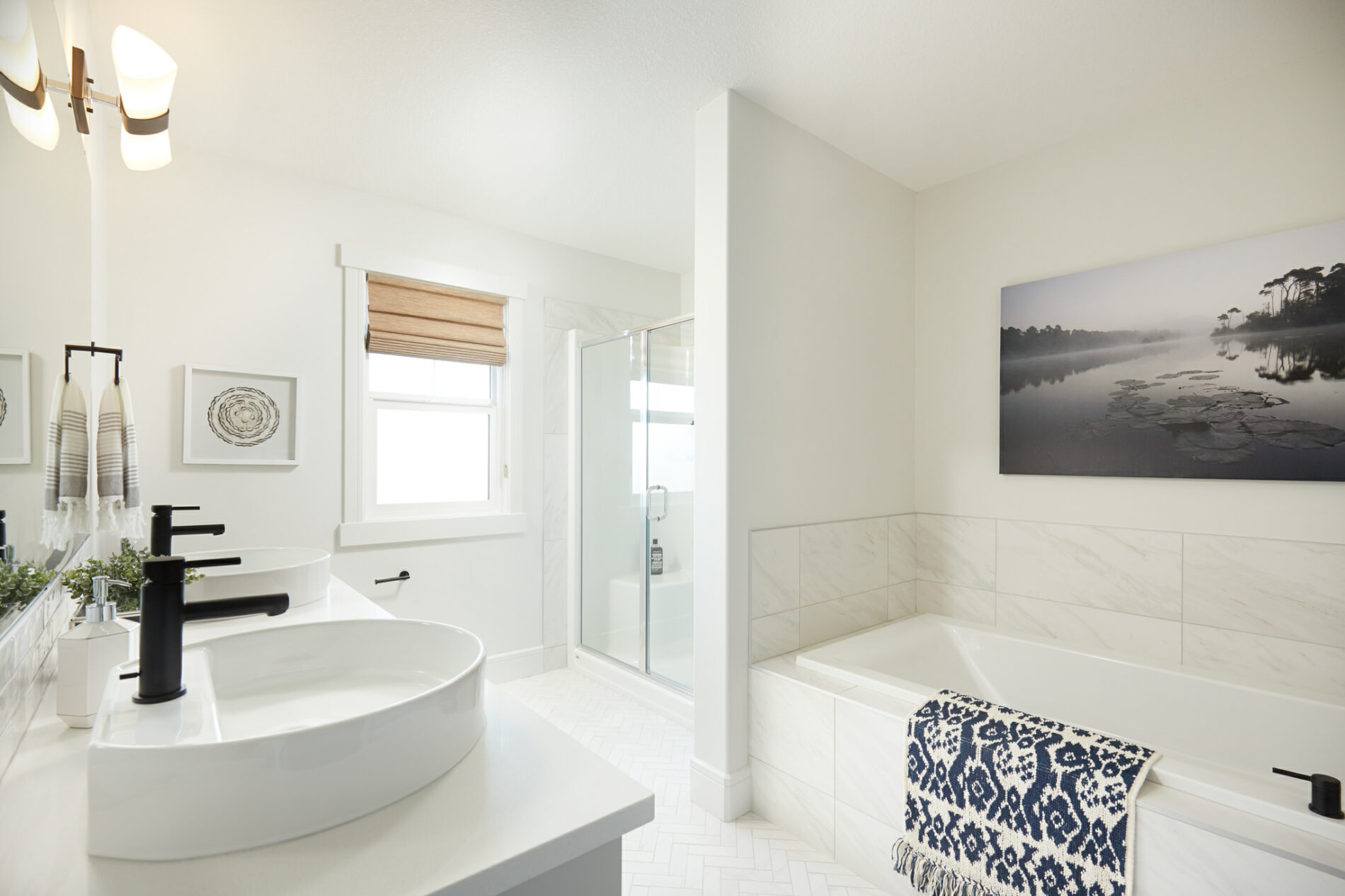 Light and bright ensuite of Archer Showhome with soaker tub, free-standing shower and dual vanity with vessel sinks and black faucets