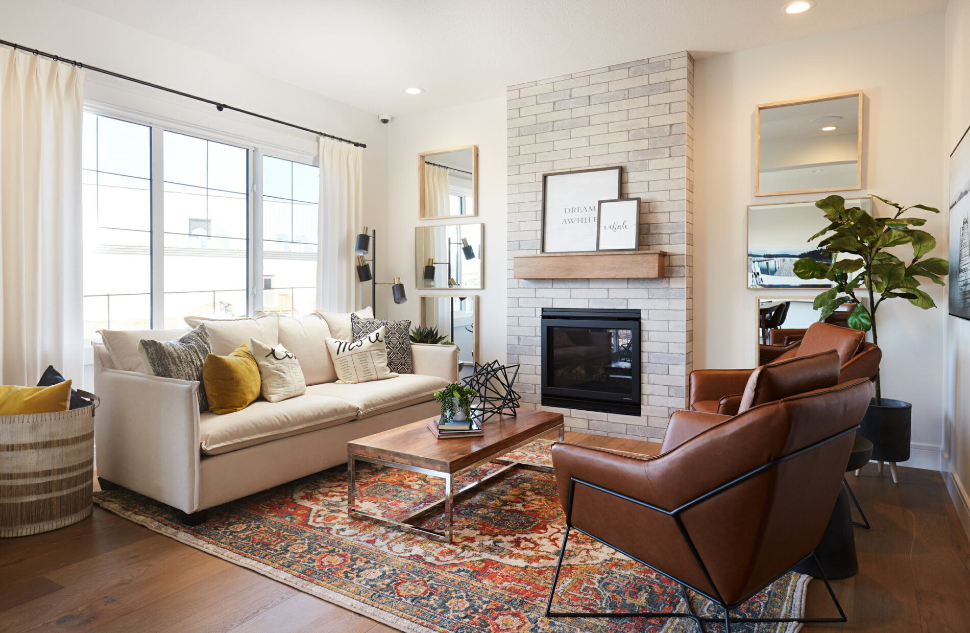 Warm and inviting great room in the Archer showhome with brick fireplace, stained wood mantle and farmhouse decor