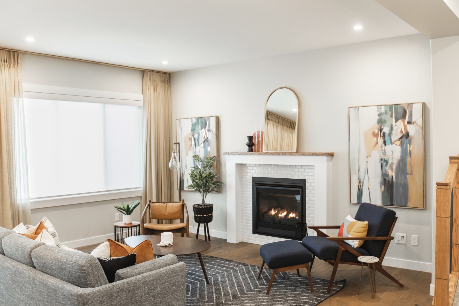 A bright mid-century inspired great room with ceiling to floor gold curtains, simple fireplace and inviting and bold furniture