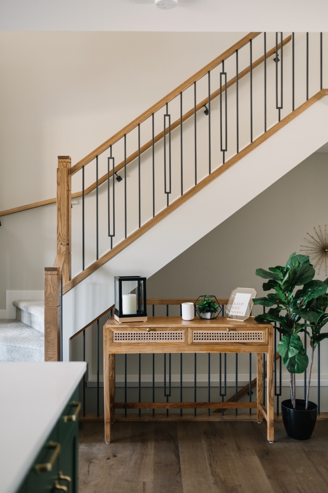 Stained wood railing leading up to the second floor of the Bianca showhome with mid-century sideboard in the nook of the stairs