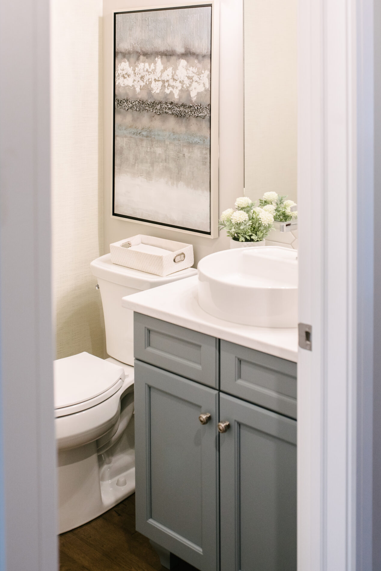 A cozy half bathroom of the Kalliope showhome in Ardrossan with light blue cabinetry, white countertops, a vessel sink and some complementing wall art