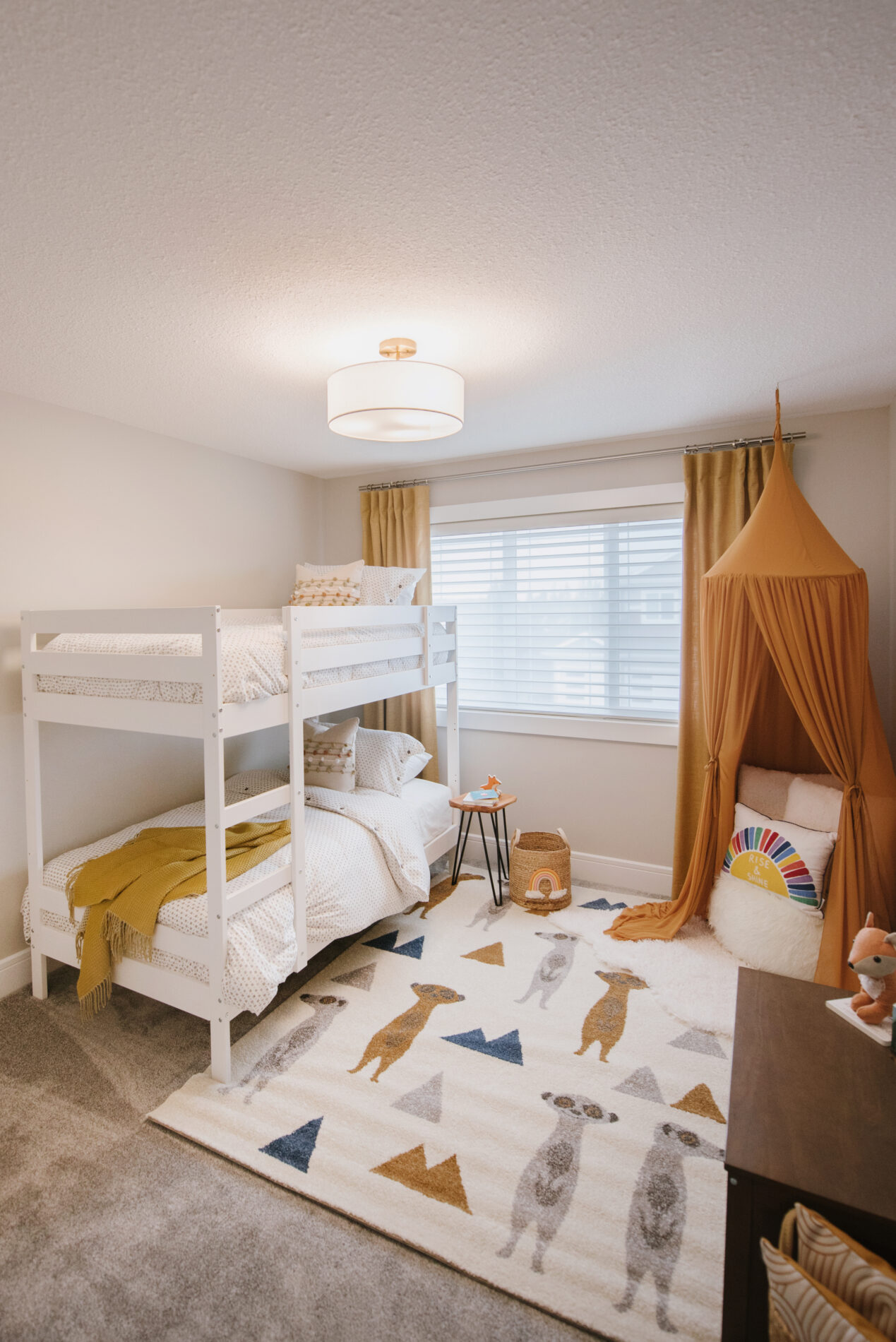 A fun secondary bedroom in the Kalliope showhome with white bunk beds on one side of the window and a reading nook with tent on the other side.