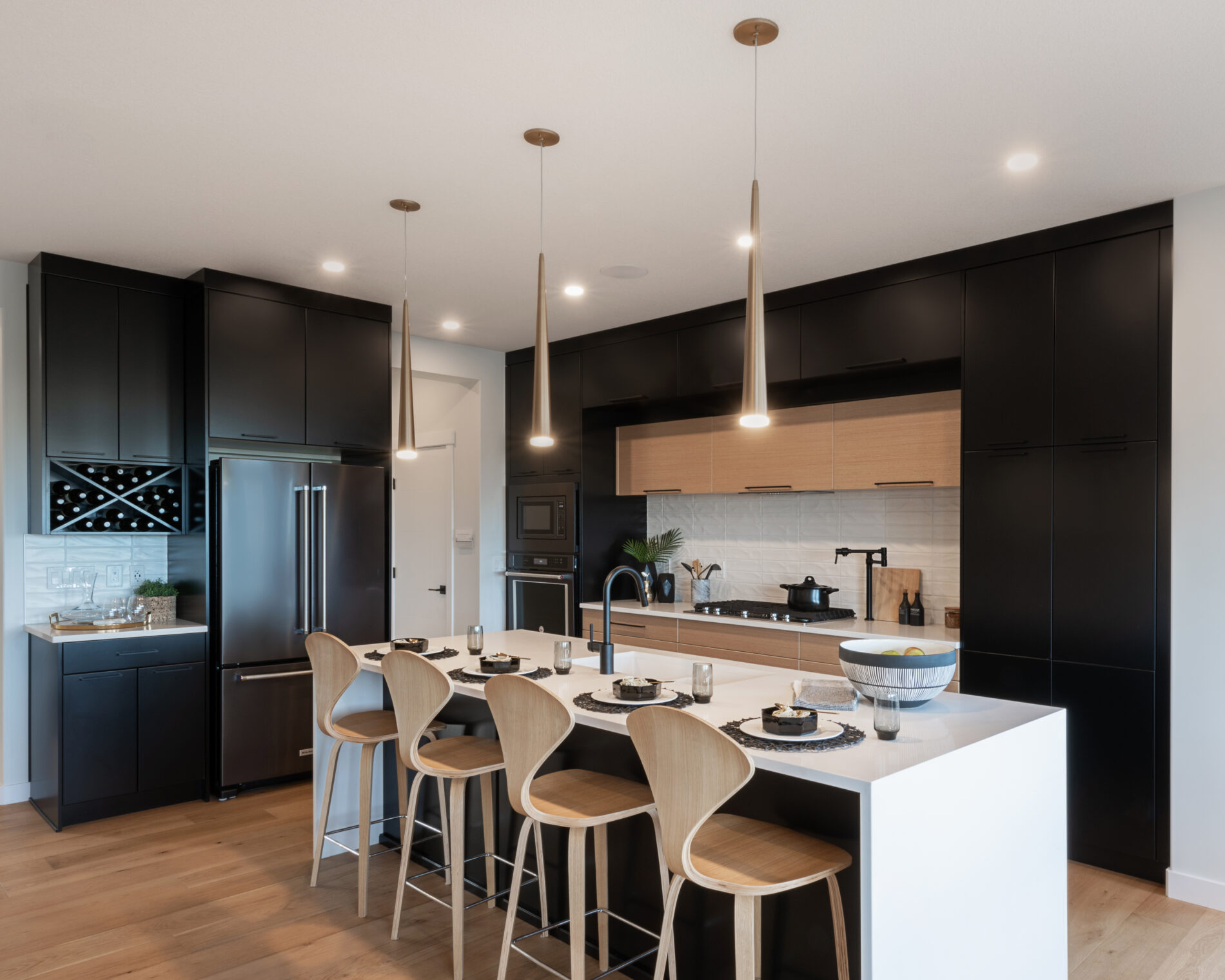 Two-toned, colour blocked, black and wood kitchen with white waterfall countertops on island