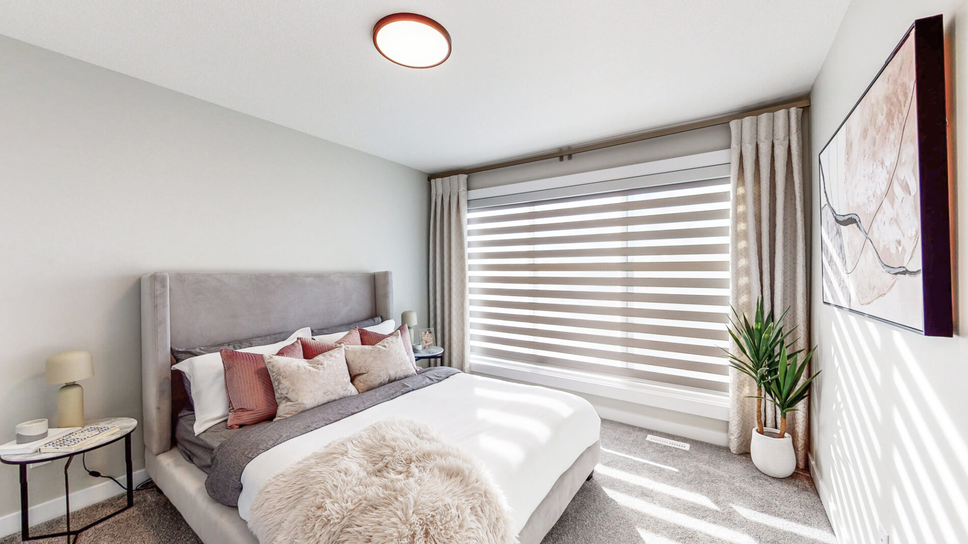 Natural light is diffused through zebra blinds covering the oversized window in a secondary bedroom