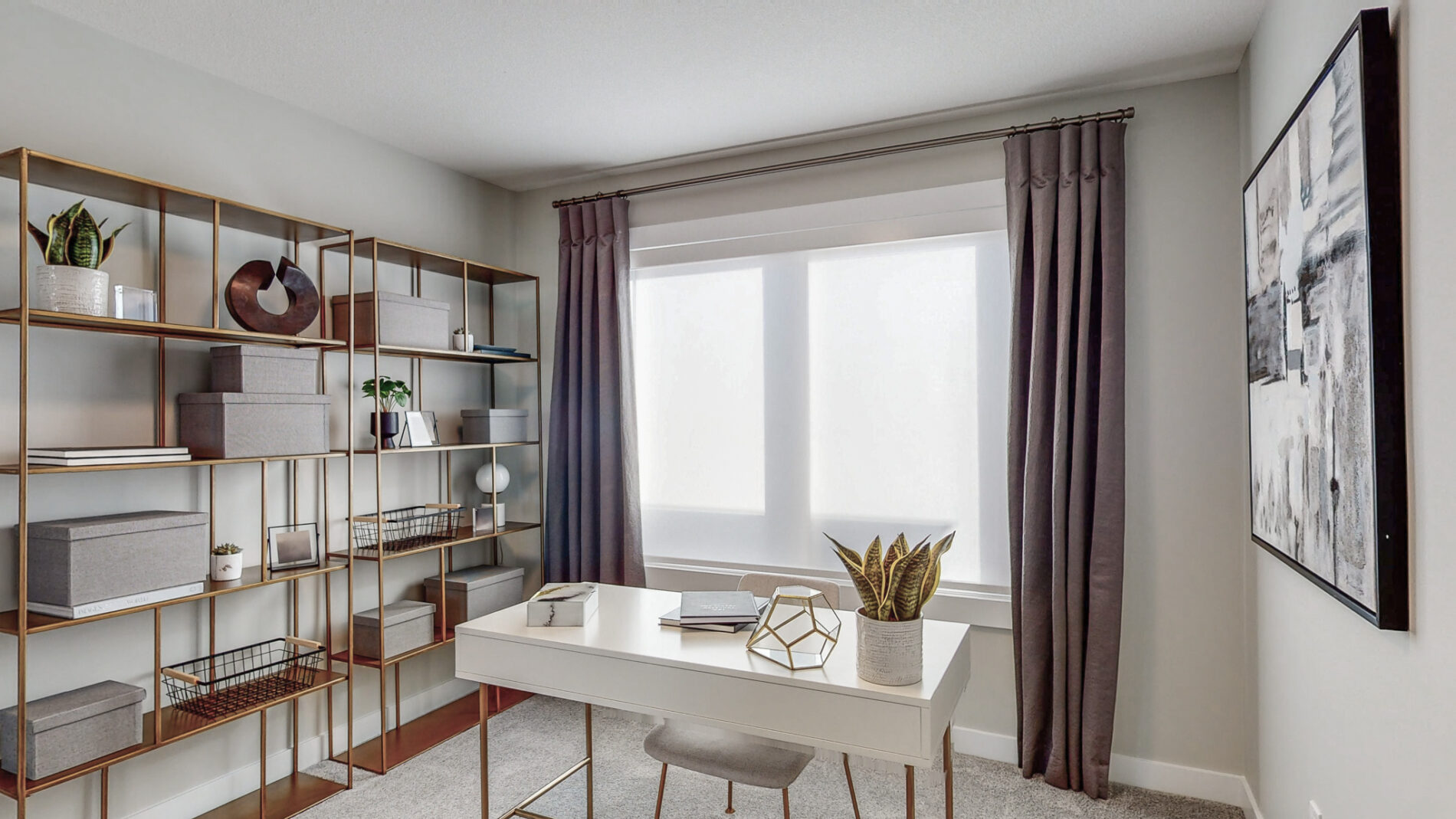 A sleek white desk is situated in front of a large window and to the side of a large book shelf in a secondary bedroom of the Cyrus showhome