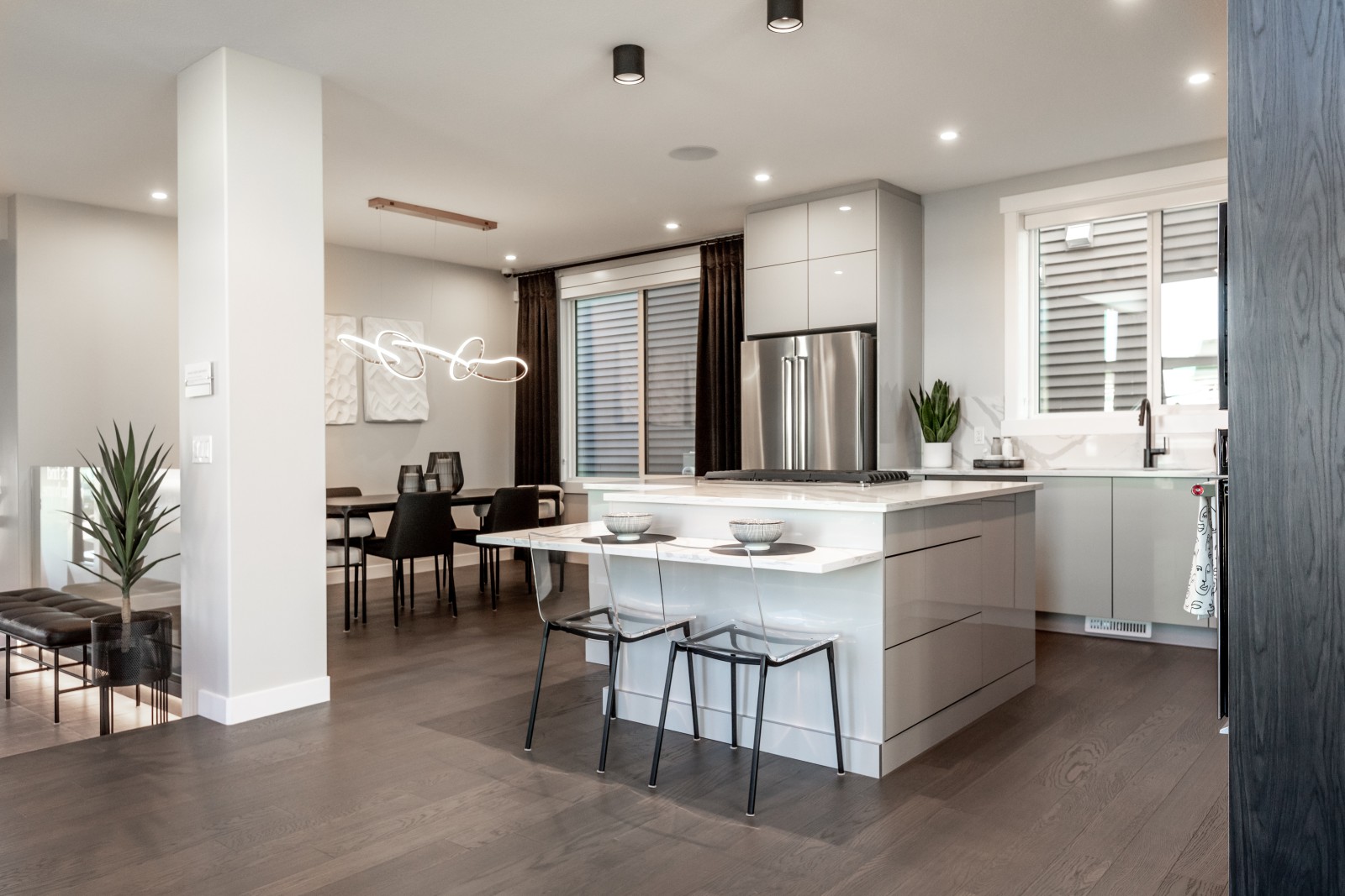 The sleek and modern kitchen of the Cyrus showhome featuring grey acrylic cabinets, white quartz countertops and a custom dropped eating bar at the island