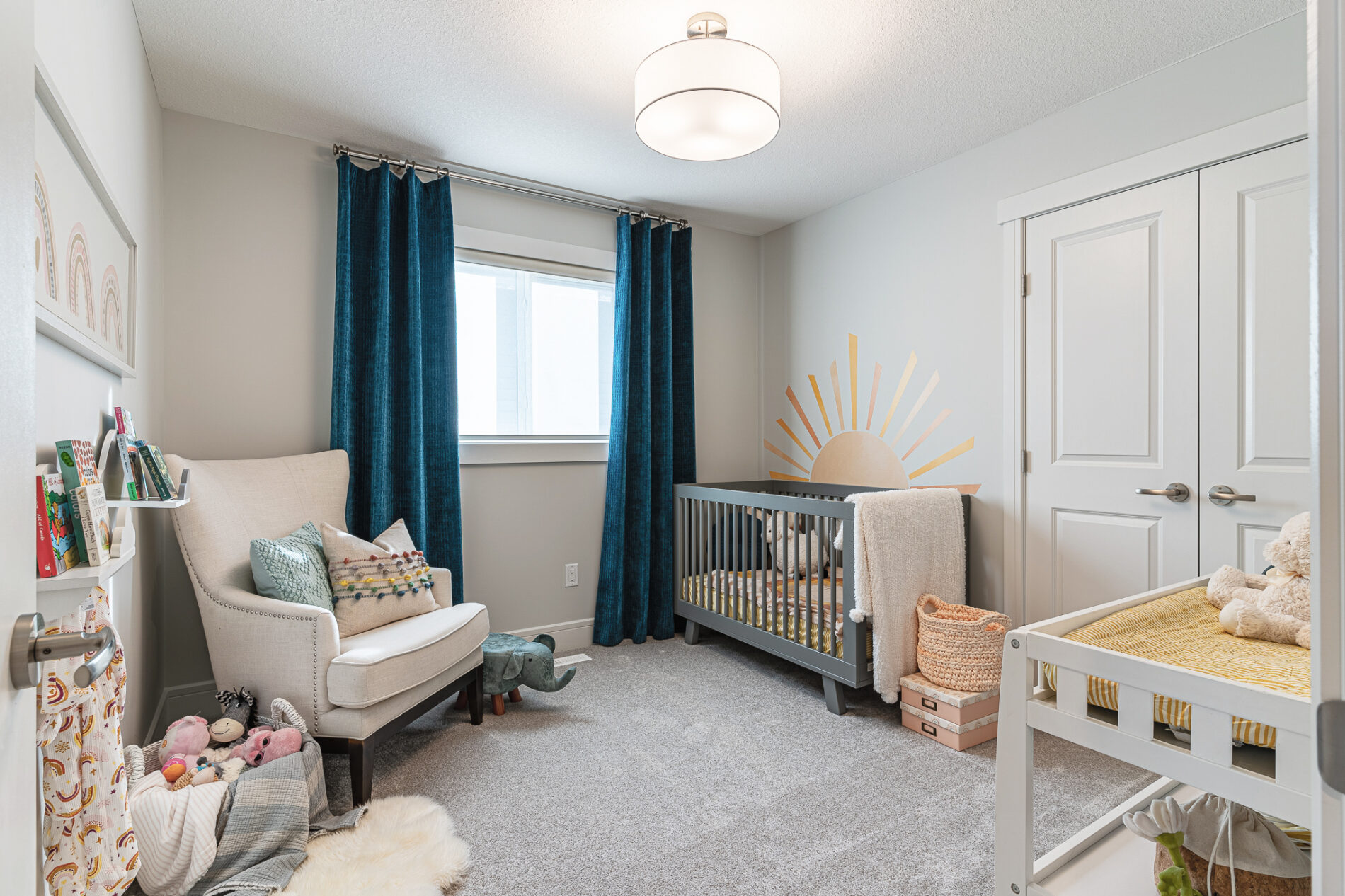 A cozy nursery room with an inviting chair across from the crib which is topped with a sun mural on the wall