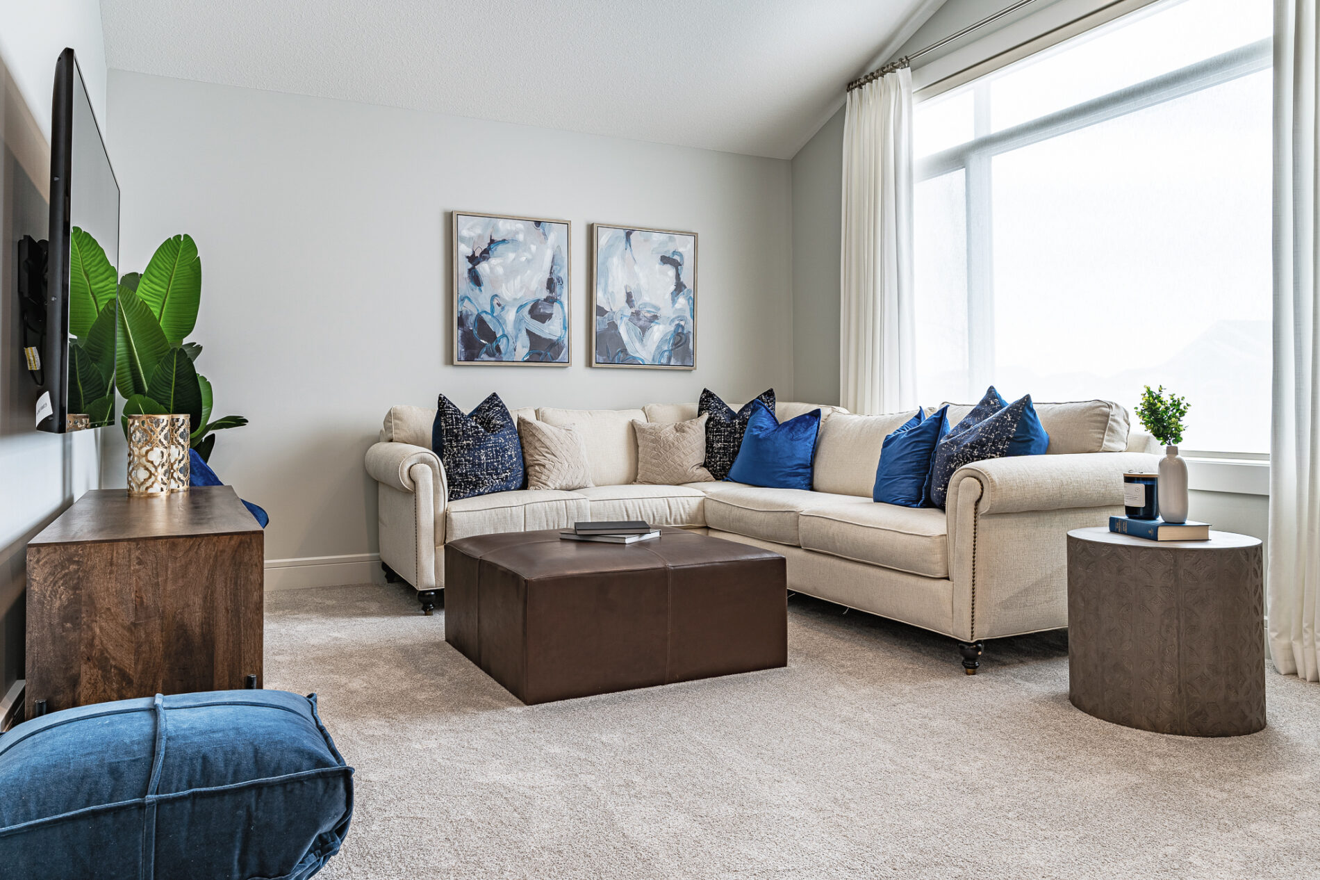 Light floods a bonus room that has an inviting sectional couch with blue accent pillows