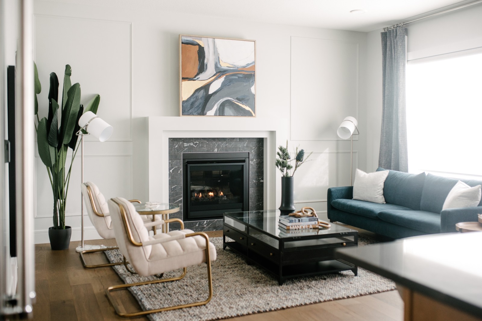 A classic fireplace with black tile and a white mantle centered in the light flooded Great Room