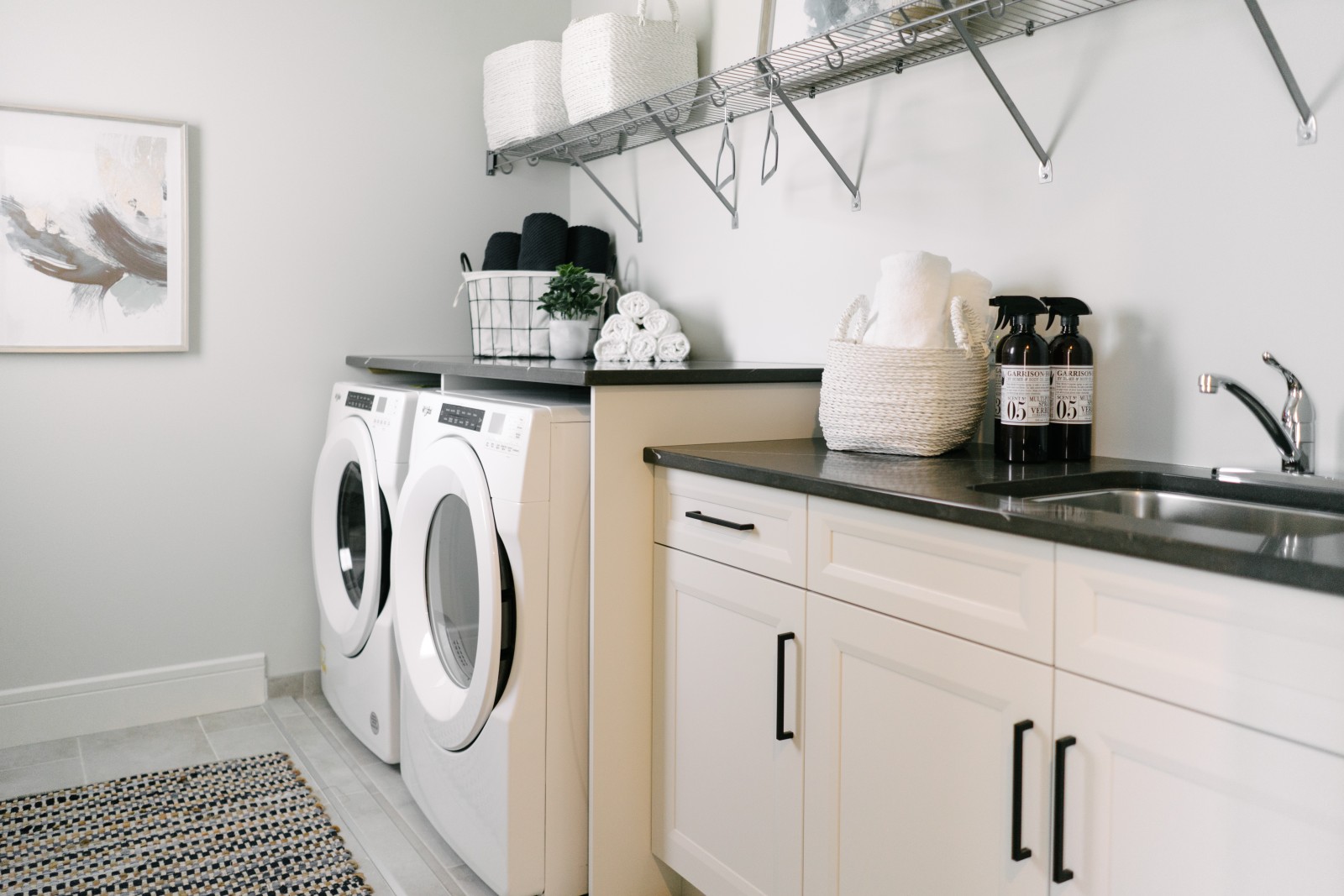Bright laundry room of the Cassius showhome with countertop over appliances and built in white cabinets with laundry sink