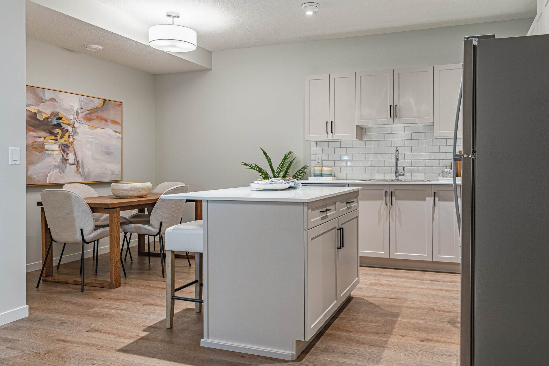 A bright white kitchen with attached dining nook with warm wood table