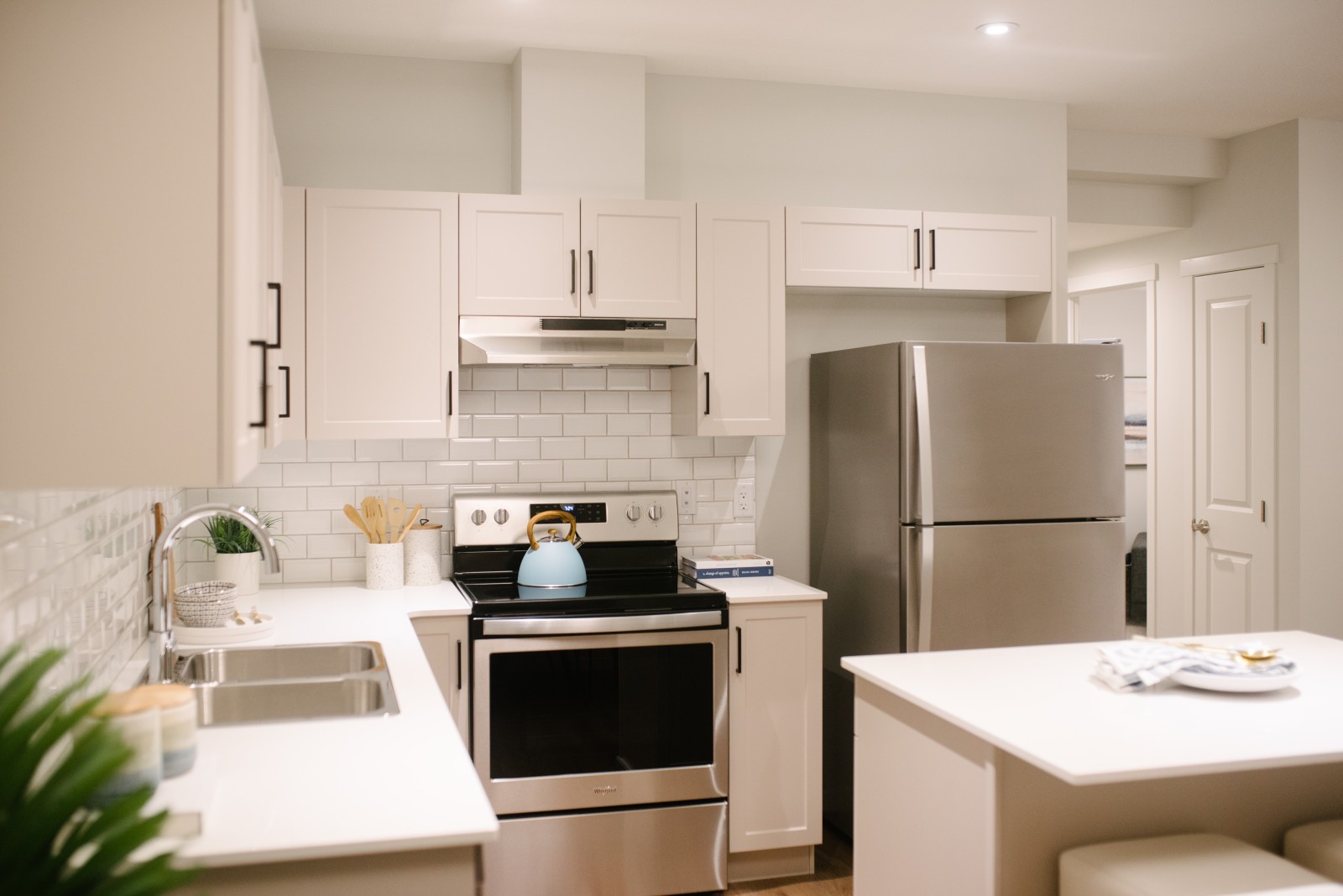 Bright white and inviting kitchen with stainless steel appliances in the Revenue Suite of the Cassius showhome