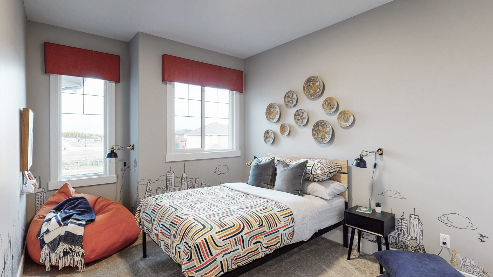 A secondary bedroom with fun multi-coloured bedding, bright accent valences on the windows and eclectic wall hangings