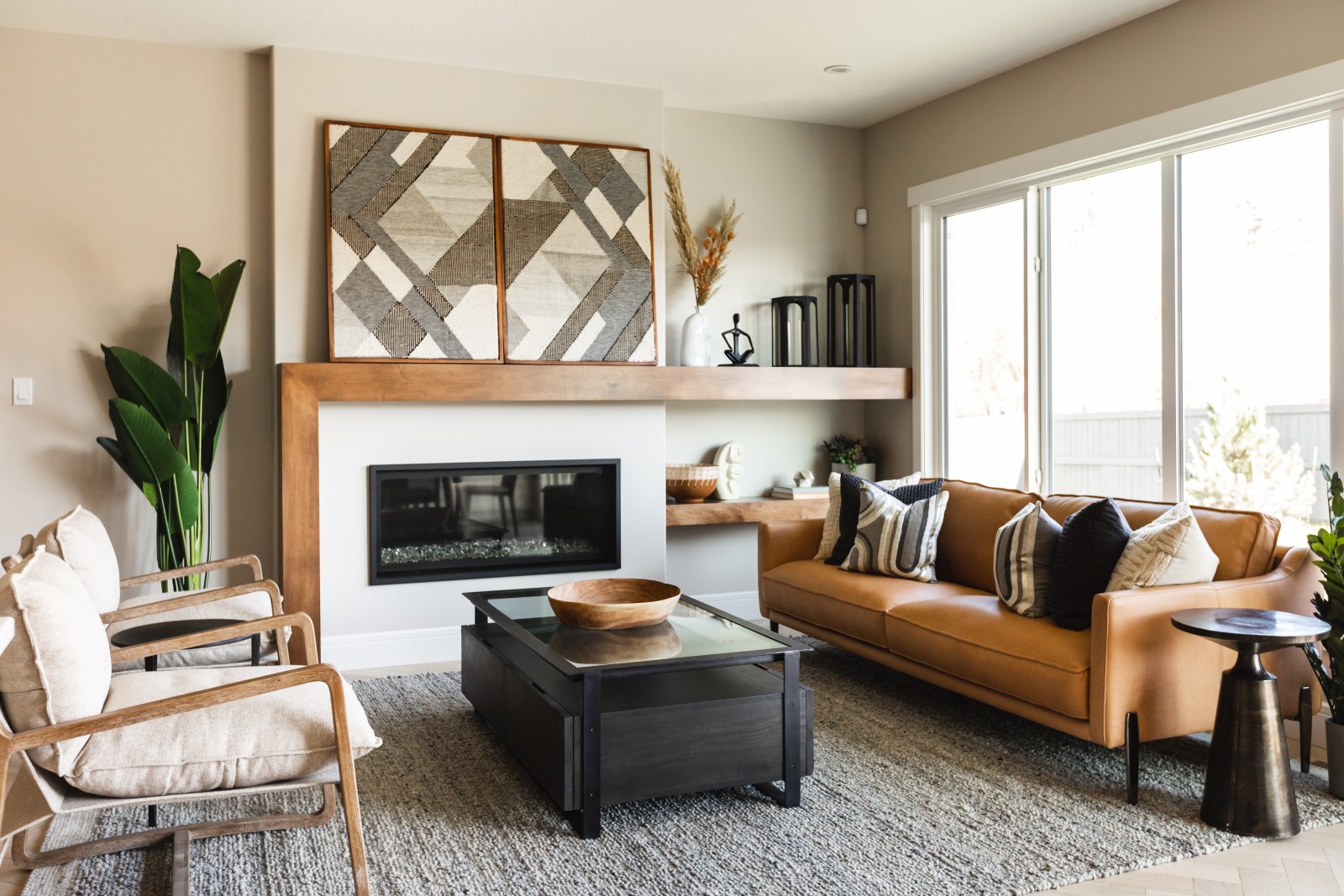 Inviting great room with congnac furniture centered around the fireplace with stained wood asymmetrical mantel topped with large art pieces