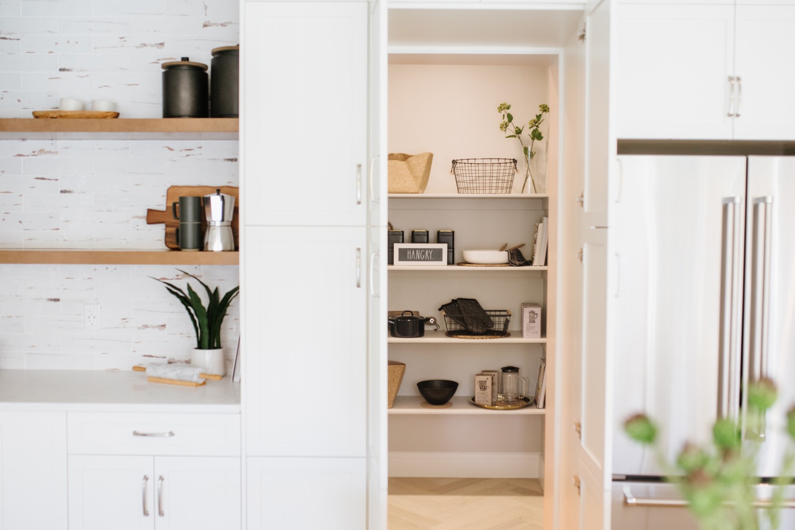 A hidden walk in pantry in a warm white kitchen in the Cyrus showhome