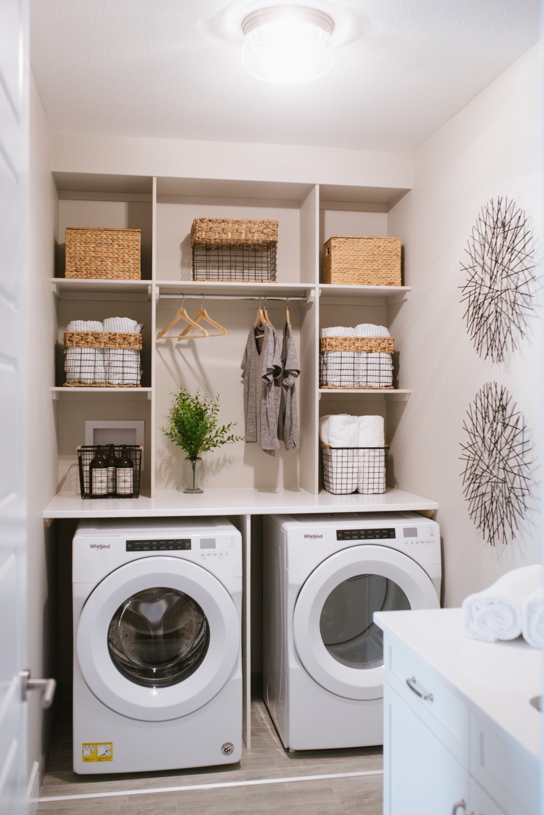 Laundry room in the Cyrus showhome with counter top above the appliances and custom built ins for ample storage and a centered hanging rod