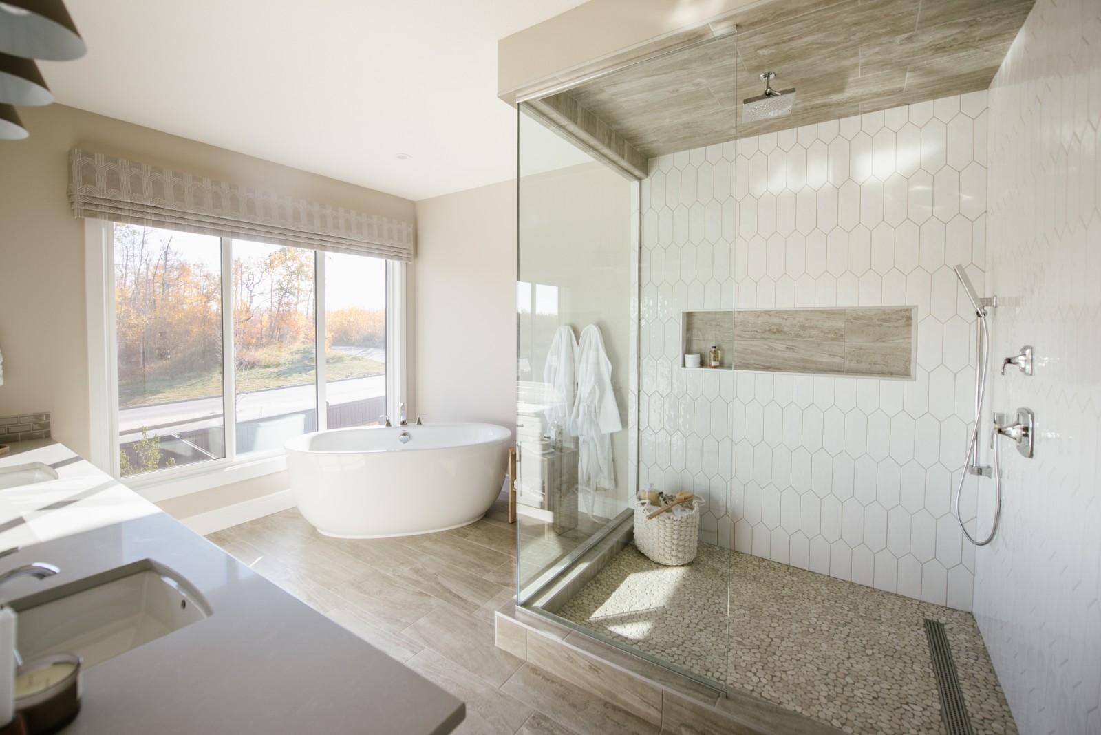 A bright master ensuite featuring a fully tiled shower with large niche and free standing tub in front of large windows