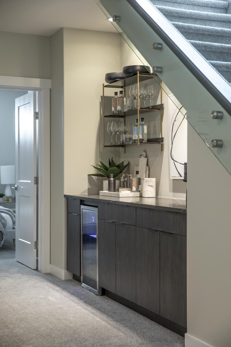 Sleek bar cabinets placed in the nook under the stairs