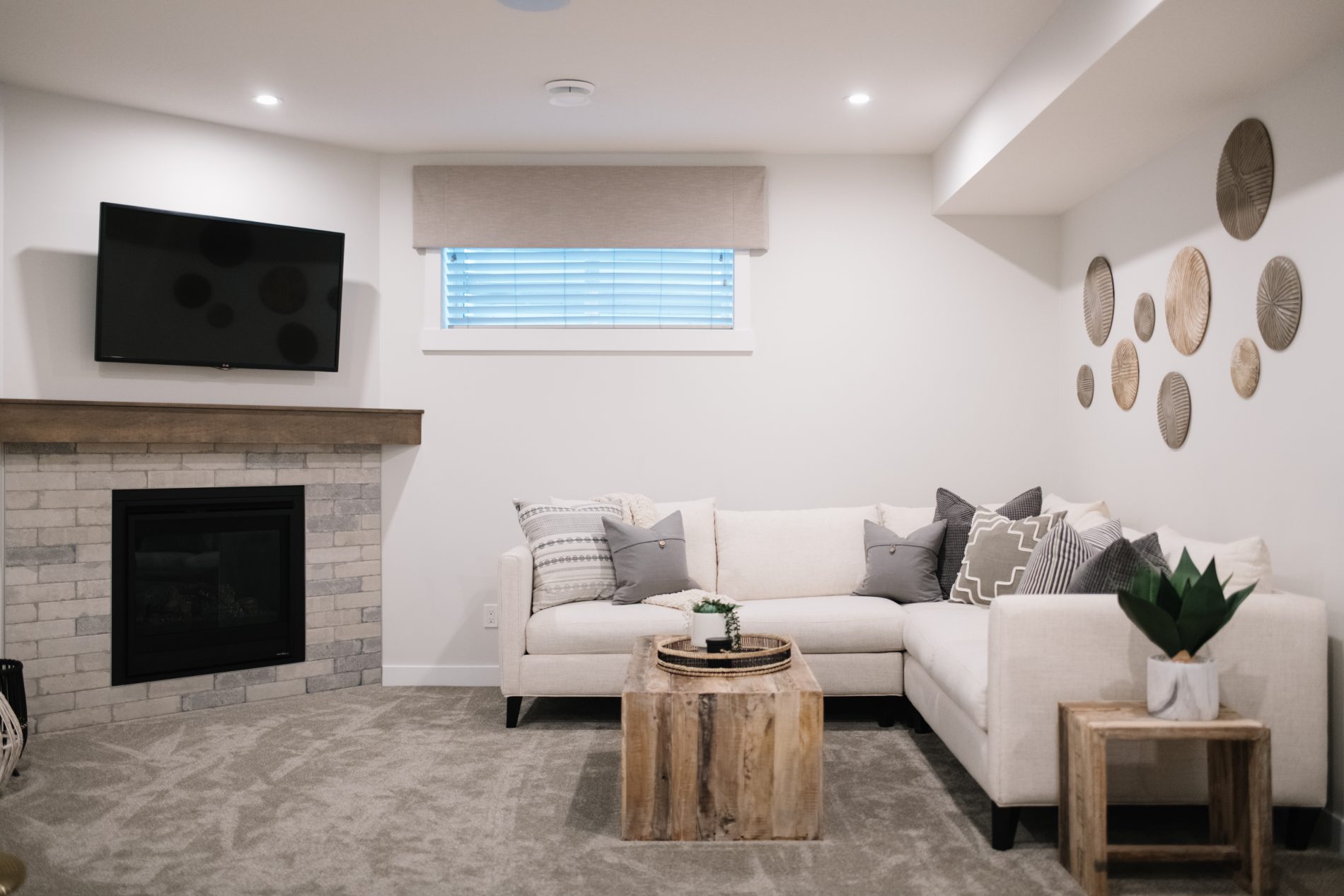 Bright and airy family room in basement with corner fireplace and comfy white sectional across from it