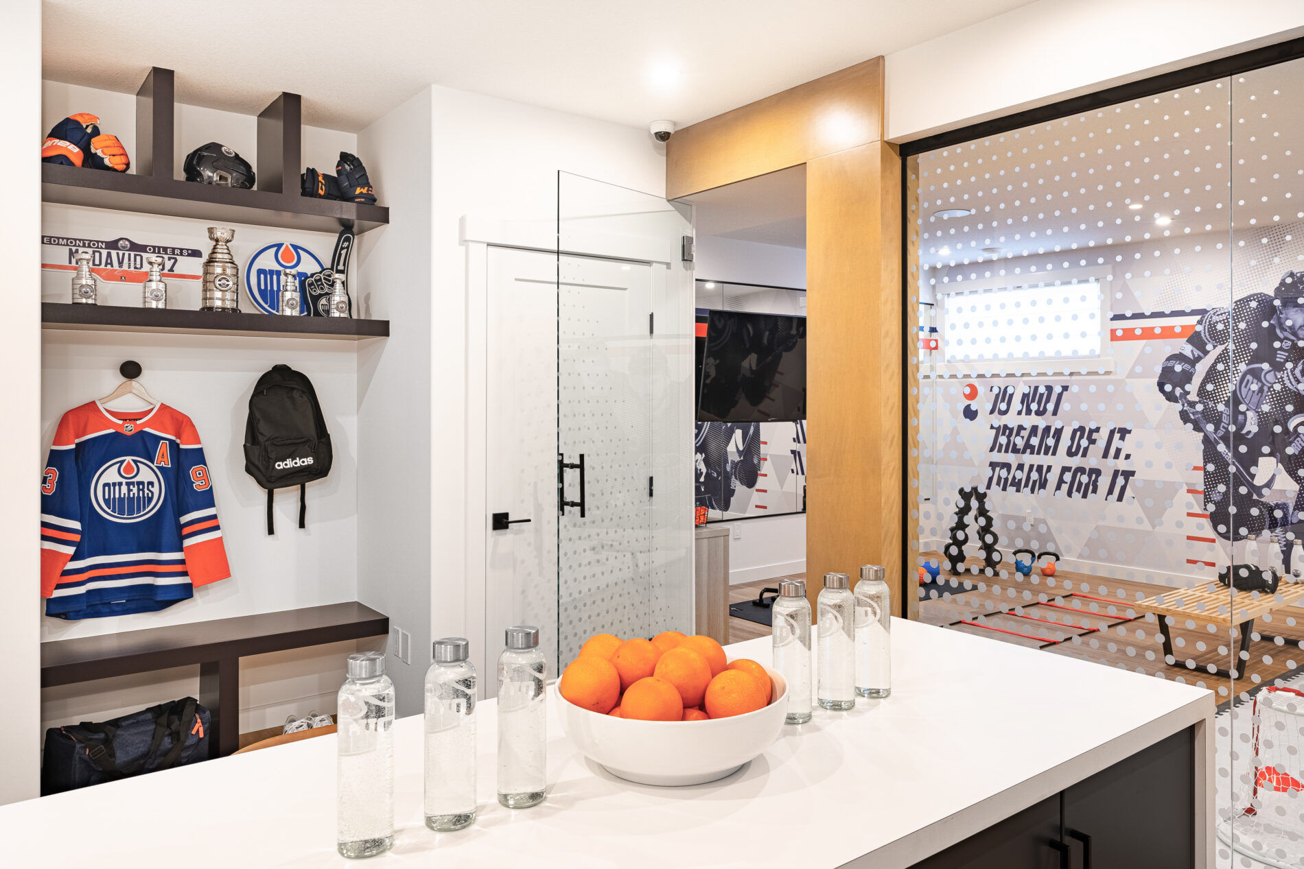 Edmonton Oilers memorabilia in shelves above a bench at the entrance to the training gym in Oilers Fan Cave Basement