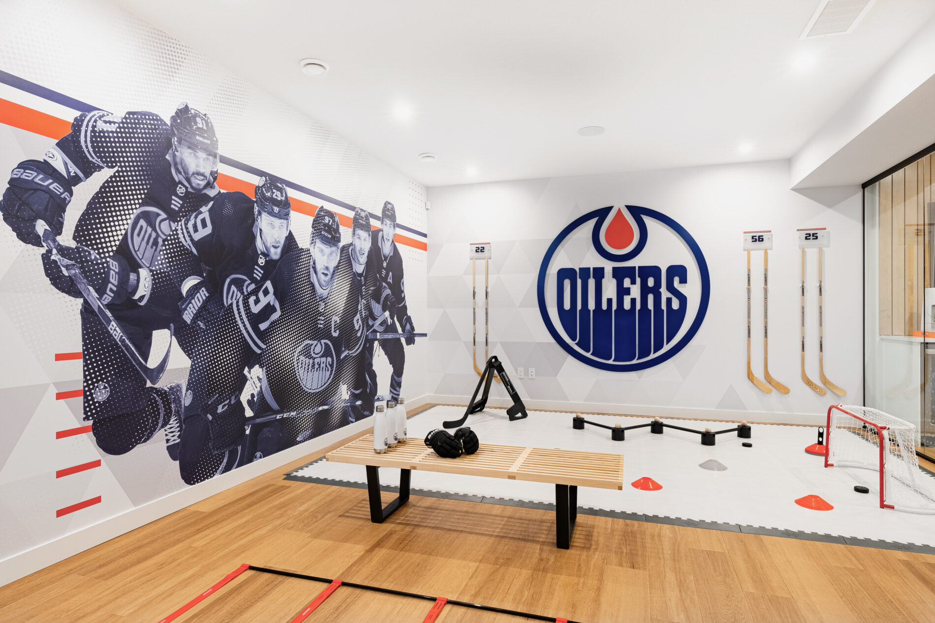 Huge full colour Oilers logo on wall adjacent to a large mural of 5 Edmonton Oilers in Oilers Fan Cave basement